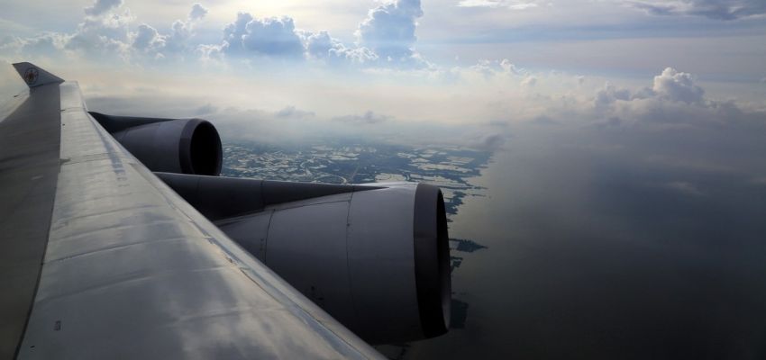an airplane wing with clouds and water